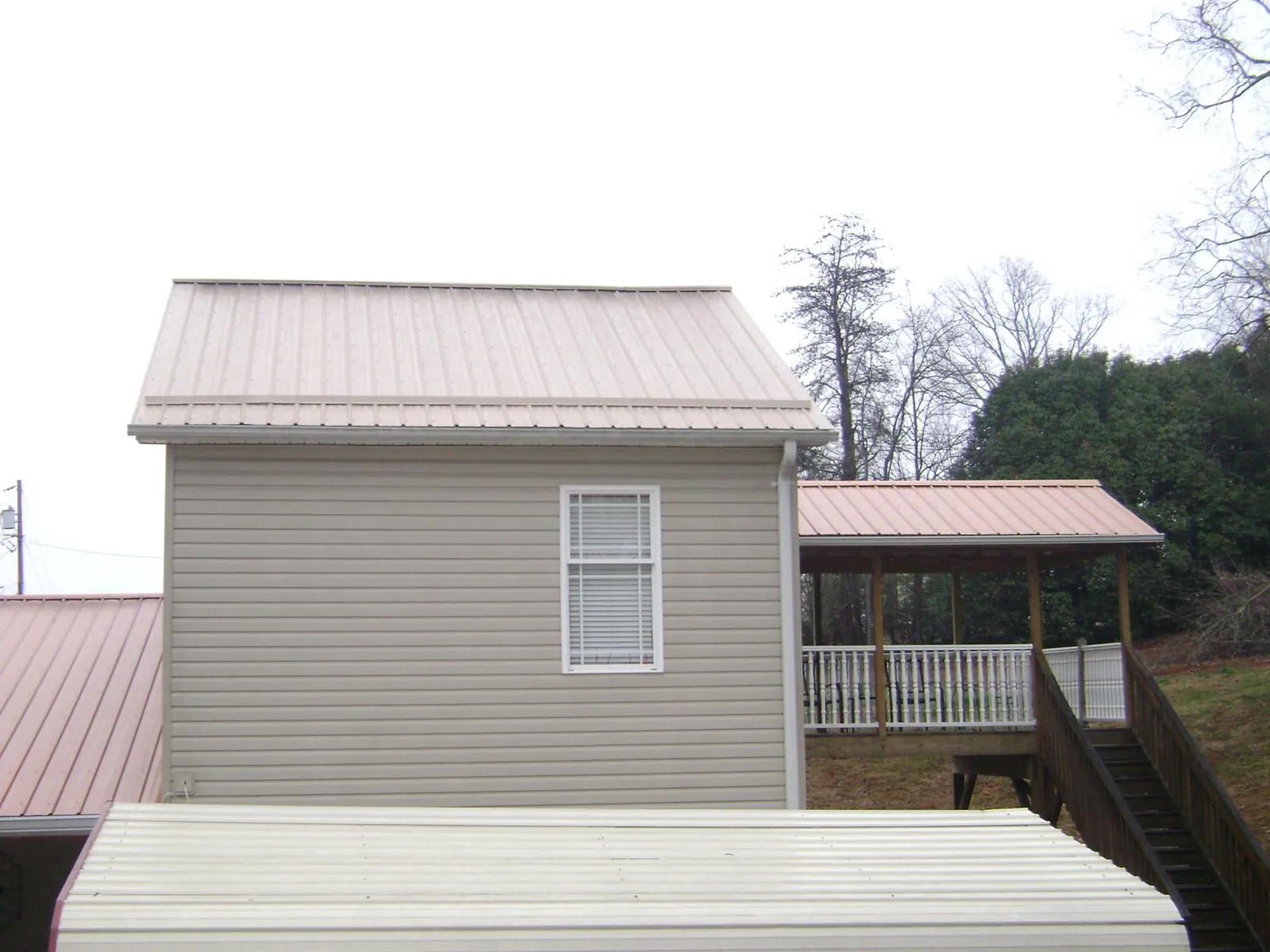 Tan metal roofs on a two story addition and attached porch, from a Roof Replacement job in Tracy